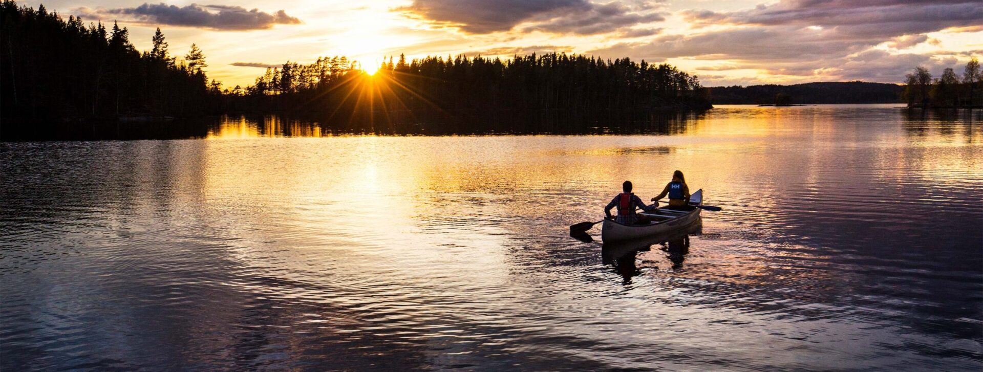 Kanot på äventyr ute på sjön i solnedgången.