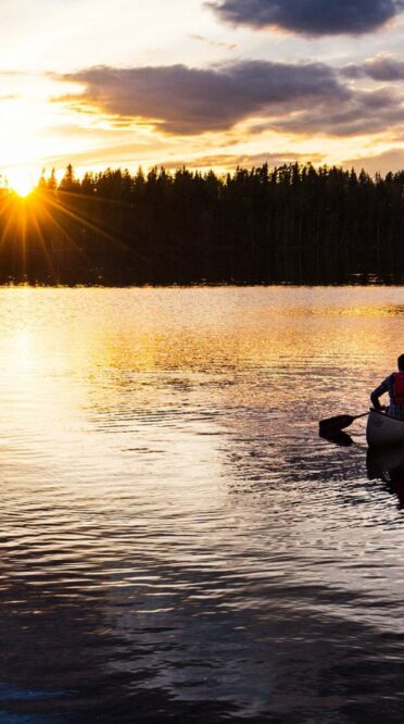 Kanot på äventyr ute på sjön i solnedgången.